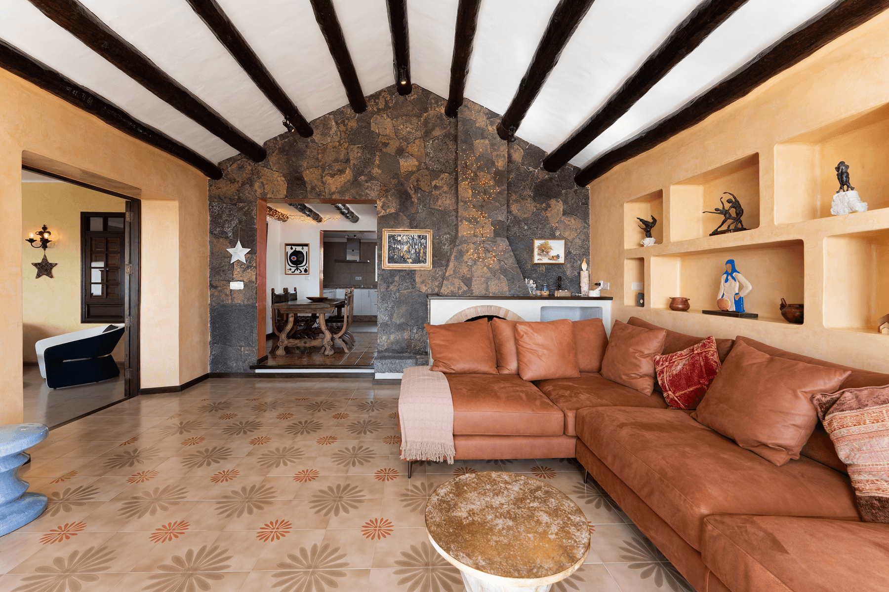 Salón con pared de piedra volcánica y vigas de madera en Lanzarote