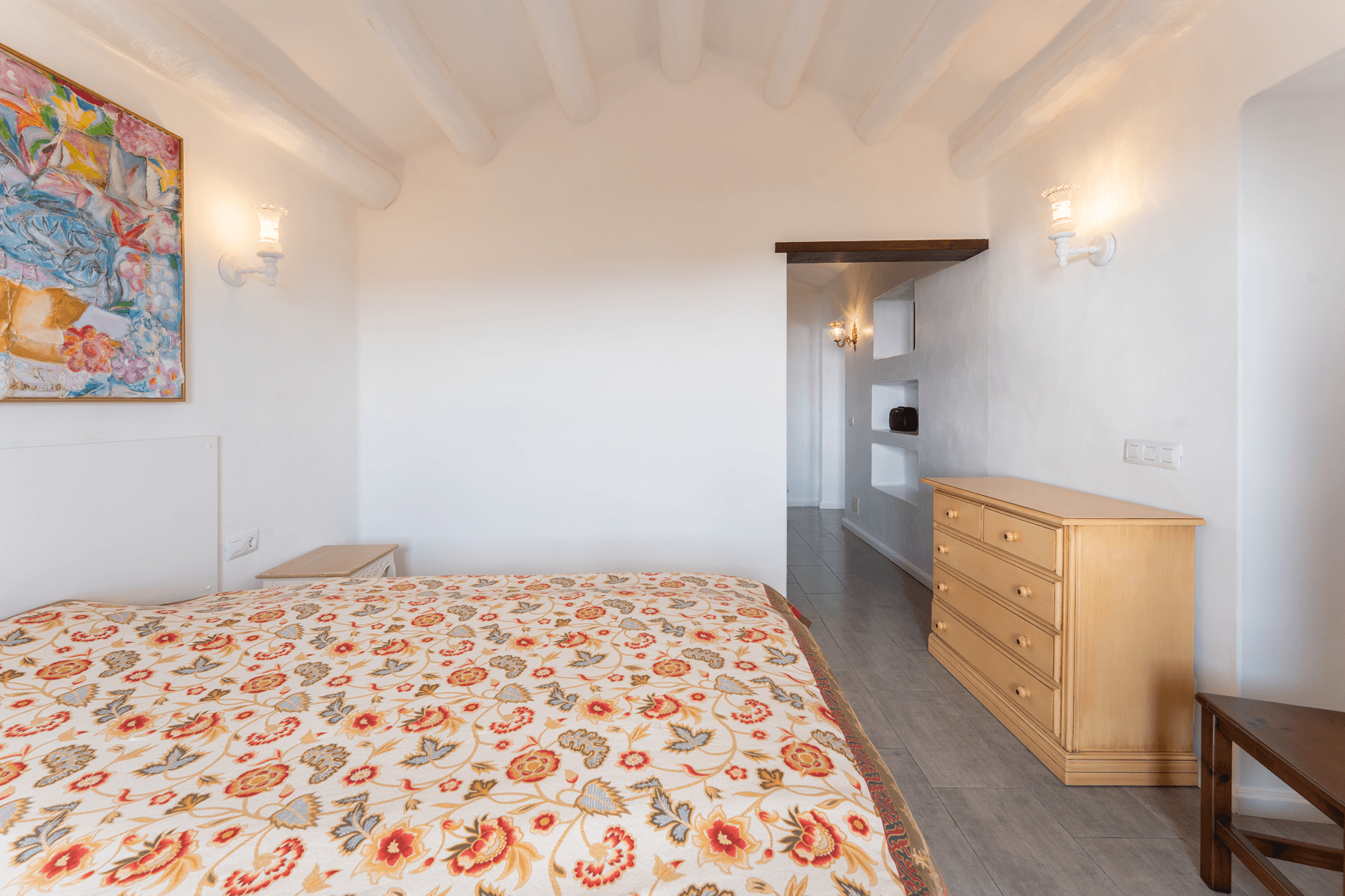 Dormitorio principal con techos abovedados, arte original y cómoda de madera en villa Lanzarote