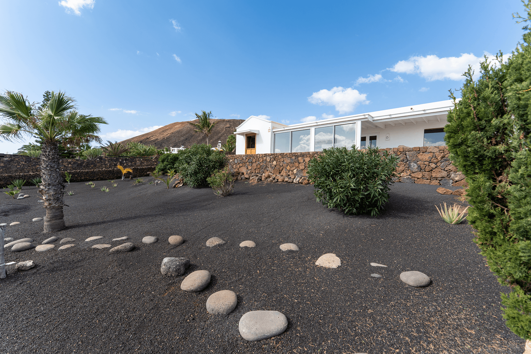 Exterior de la villa con jardín de picón negro y palmeras en Playa Blanca, Lanzarote