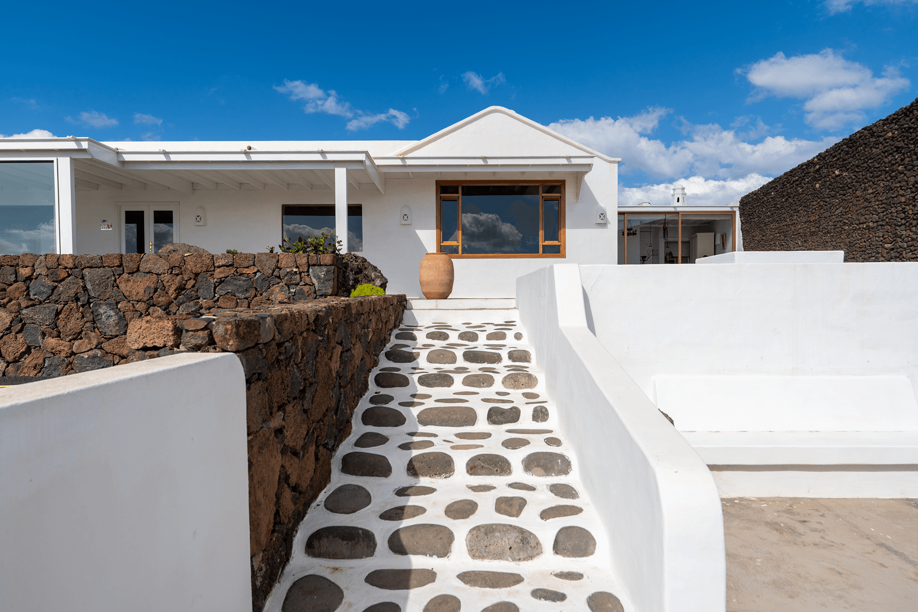 Entrada principal de villa blanca con camino de piedra volcánica en Lanzarote